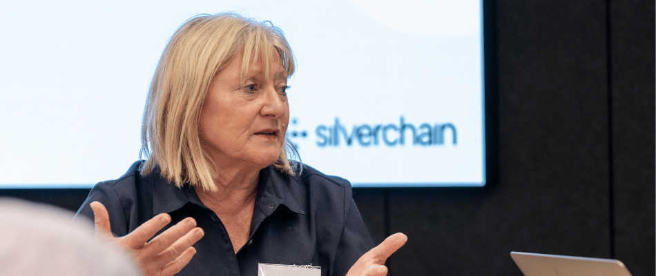 A lady speaks with a silverchain logo in the background